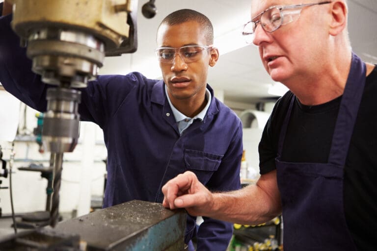 Engineer Teaching Apprentice To Use Milling Machine